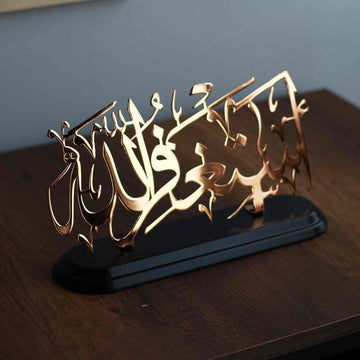 Shiny copper Astaghfirullah metal table decor, angled view of the cut calligraphy on its black stand