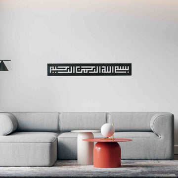Metall-Wandkunst mit Bismillah in Kufi-Schrift in Schwarz, an einer hellen Wand über einem grauen Sofa