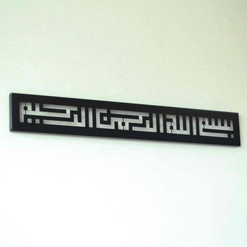 Metall-Wandkunst mit Bismillah in Kufi-Schrift in Schwarz, an einer weißen Wand, niedriger seitlicher Winkel