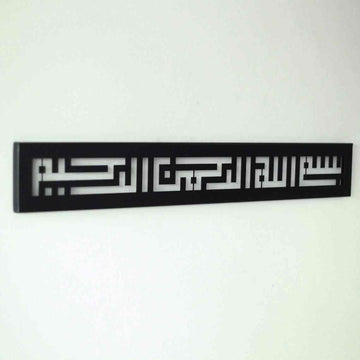 Metall-Wandkunst mit Bismillah in Kufi-Schrift in Schwarz, an einer weißen Wand, Schrägansicht mit den ausgeschnittenen Buchstaben