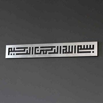 Metall-Wandkunst mit Bismillah in Kufi-Schrift in Silber, an einer dunkelgrauen Wand, leicht schräg