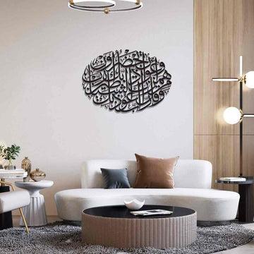 لوحة جدارية معدنية سوداء بدعاء الحماية من الشر فوق أريكة بيضاء منحنية في غرفة المعيشة