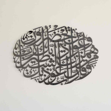لوحة جدارية معدنية بيضاوية سوداء بدعاء الحماية من الشر على جدار كريمي، منظر مائل قليلا
