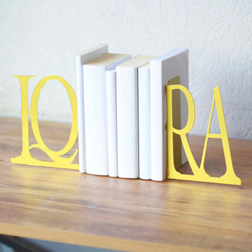 Gold IQRA bookends with white books, slightly angled front view on a wooden table