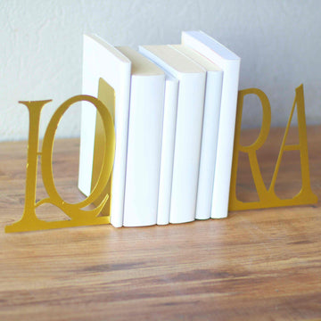Gold IQRA Latin bookends with white books, close angled view of the Q letter