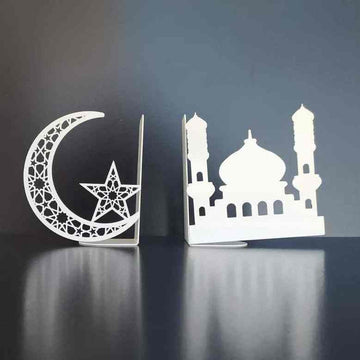 Weiße Metall-Buchstützen mit Halbmond samt Stern und Moschee-Silhouette auf einer dunklen spiegelnden Fläche