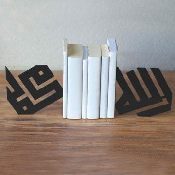 Schwarze kufische Buchstützen Allah und Mohammed auf einem Holzregal mit einem Stapel weißer Bücher dazwischen