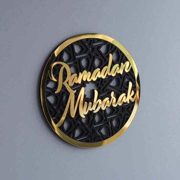Gold Ramadan Mubarak circular wall decor with script over a black geometric pattern, angled on a gray wall