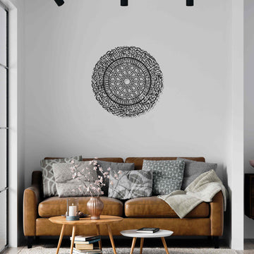 Schwarze runde Metall-Wandkunst mit Sure Al-Fatihah an einer weißen Wand über einem braunen Ledersofa