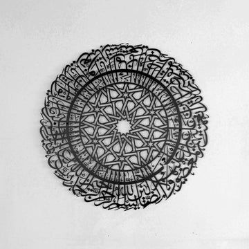 Schwarze runde Metall-Wandkunst mit Sure Al-Fatihah an einer hellen Wand, schräge Vorderansicht