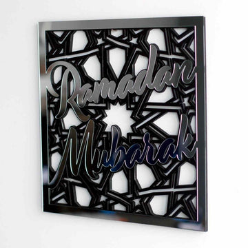 Close-up of silver mirror Ramadan Mubarak lettering over the star pattern on a white wall