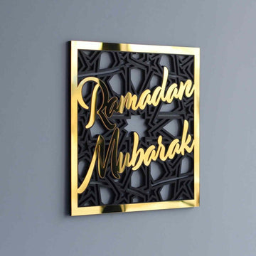 Gold Ramadan Mubarak square wall art with black geometric pattern, front angle on a gray wall