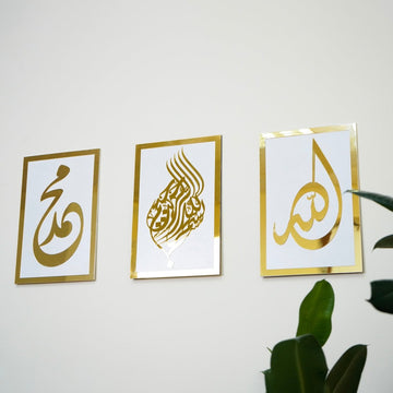 Basmala, Allah and Muhammad wooden wall art set, Gold on White, straight view beside a plant