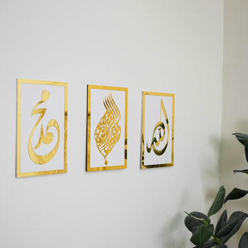 Basmala, Allah and Muhammad wooden wall art set, Gold on White, angled view with a plant at the edge