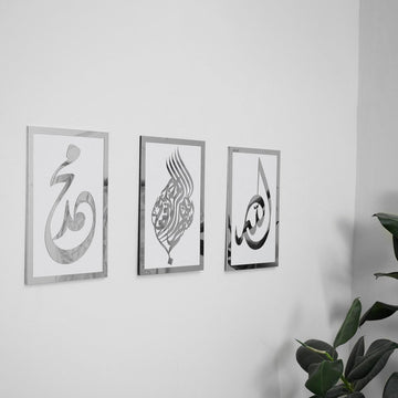 Basmala, Allah and Muhammad wooden wall art set, Silver on White, angled view with a plant at the edge