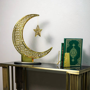 Small Shiny Gold crescent and star decor on a console beside a green Quran and a Quran stand