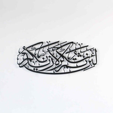 لوحة جدارية معدنية سوداء لسورة إبراهيم الآية 7، منظر أمامي للخط البيضاوي على جدار أبيض
