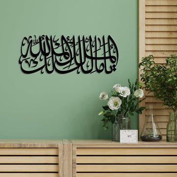 لوحة جدارية معدنية سوداء «يا مالك الملك، الملك لله» على جدار أخضر فوق خزانة خشبية